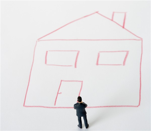 En person i form av en figur står foran et opptegnet hus.